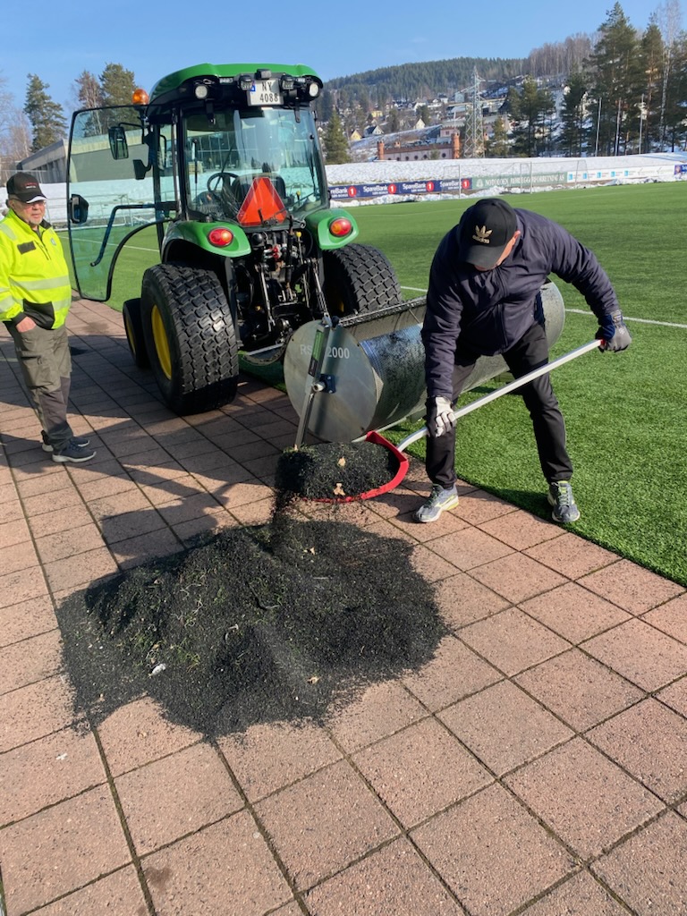 Frivillige som rydder granulat langs banen